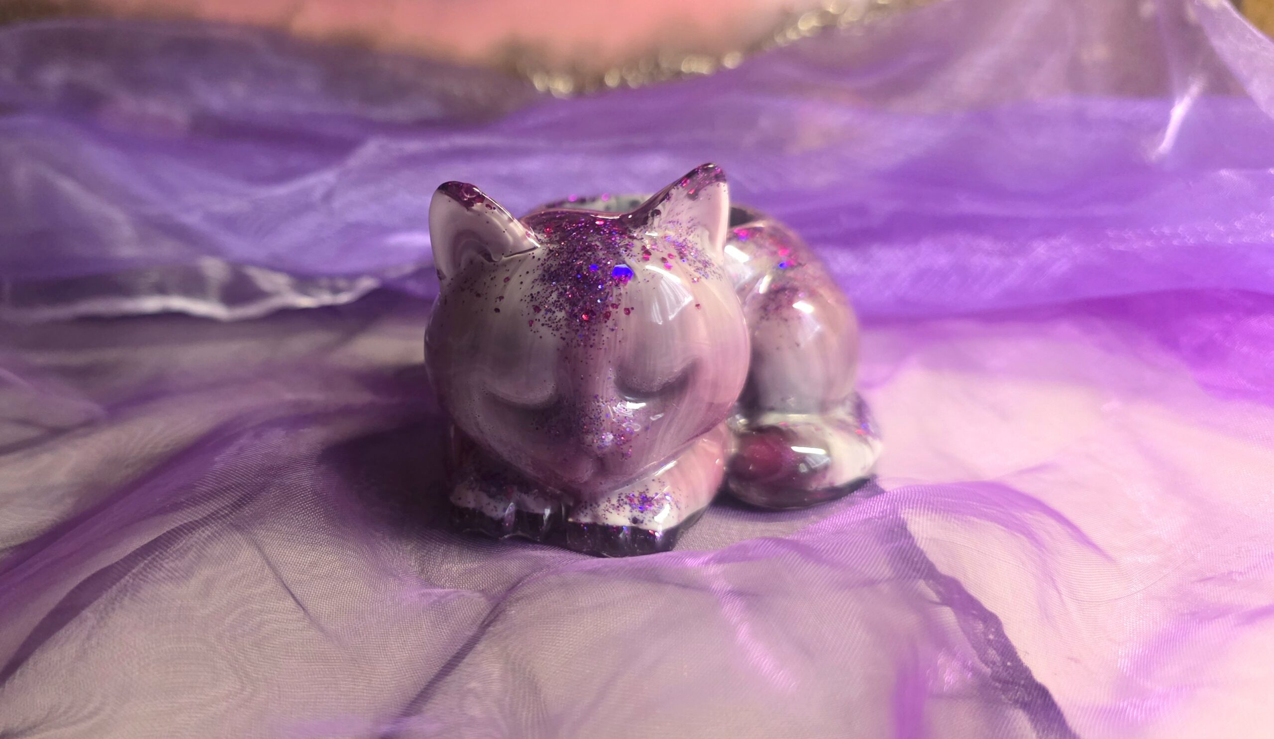 Handgefertigter Teelichthalter in Form einer schlafenden Katze aus Epoxidharz – Edles Design in Lila, Schwarz und Weiß mit funkelndem Glitzer-Finish, ein Unikat von Traumharz.