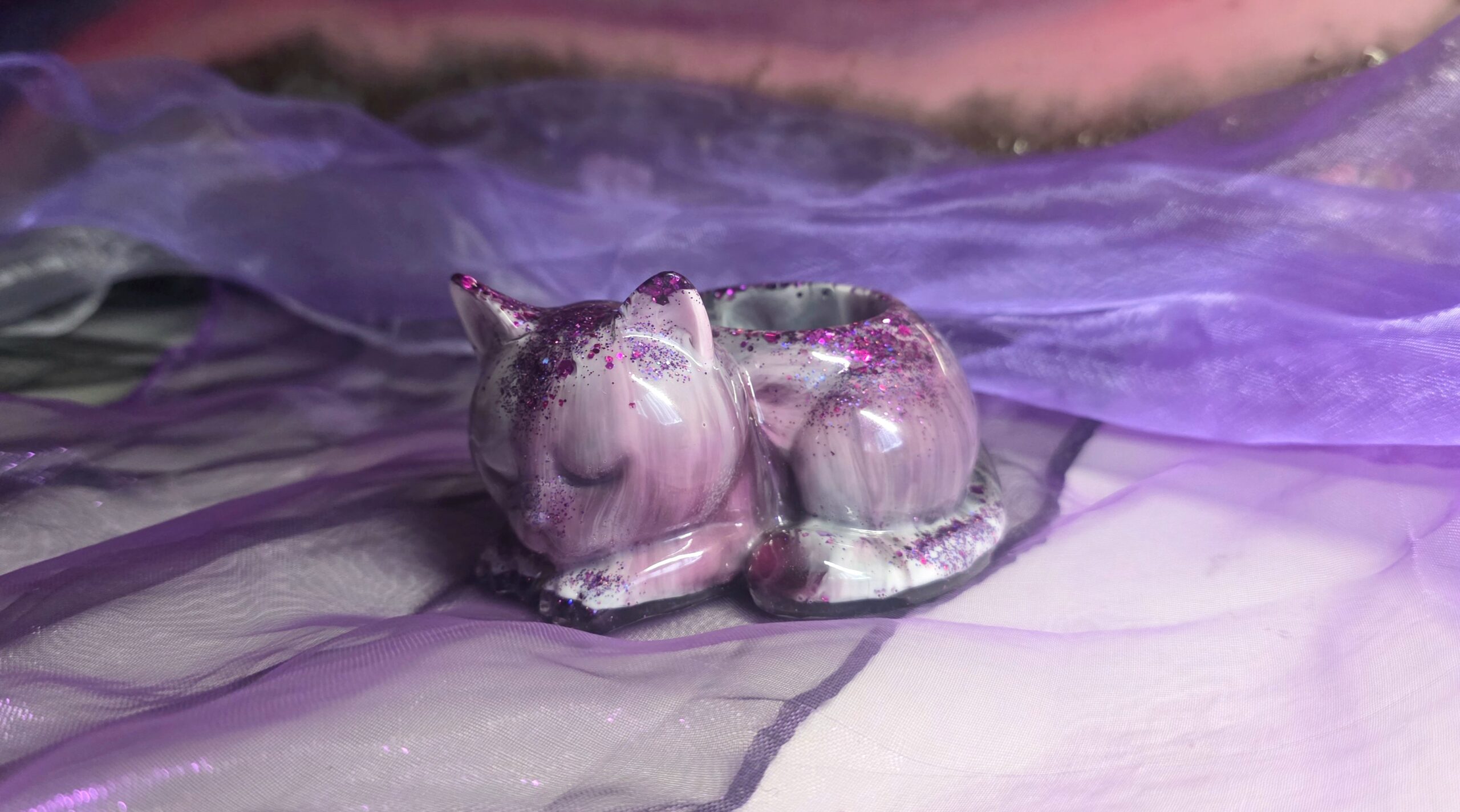Handgefertigter Teelichthalter in Form einer schlafenden Katze aus Epoxidharz – Edles Design in Lila, Schwarz und Weiß mit funkelndem Glitzer-Finish, ein Unikat von Traumharz.