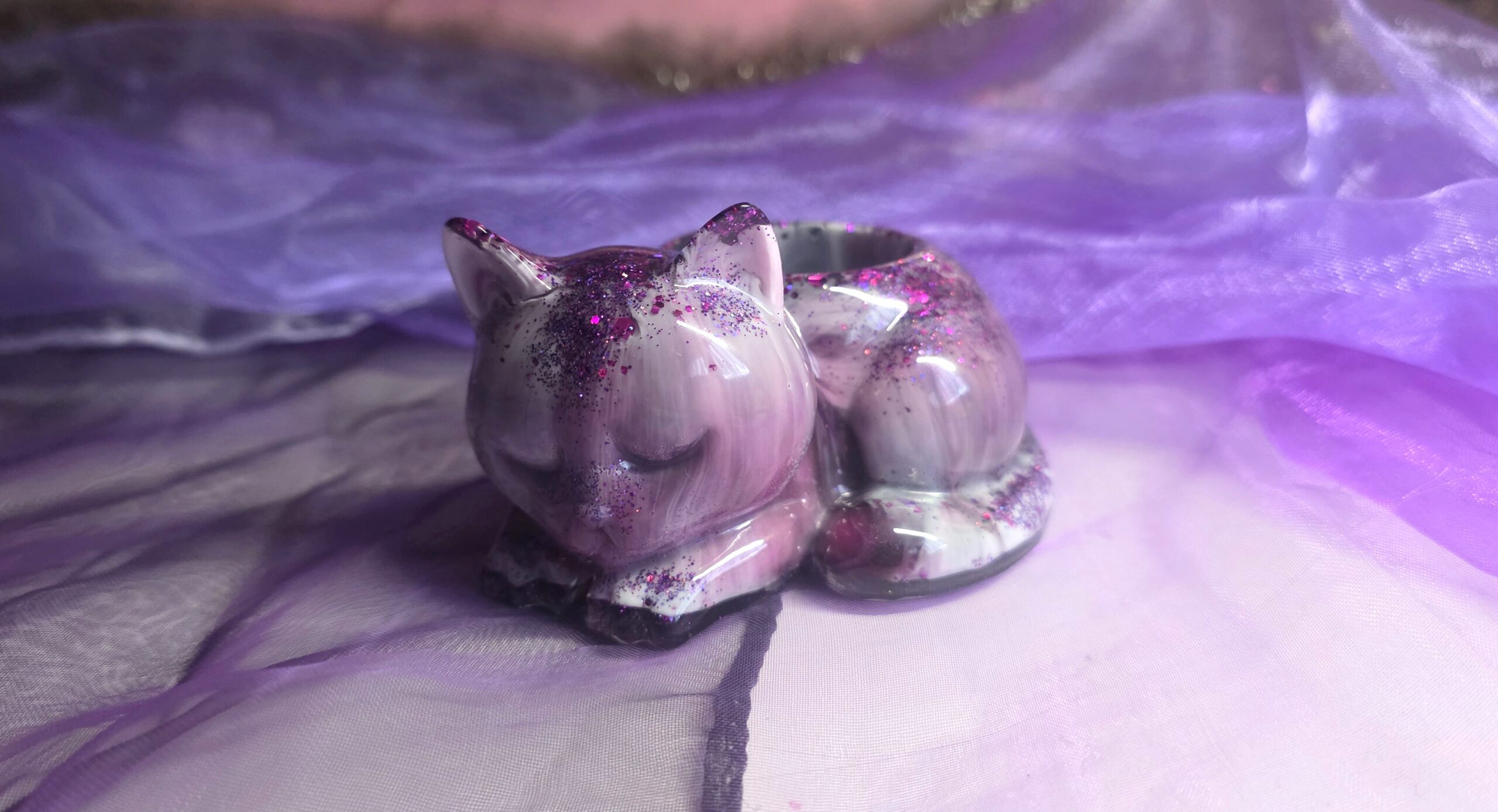 Handgefertigter Teelichthalter in Form einer schlafenden Katze aus Epoxidharz – Edles Design in Lila, Schwarz und Weiß mit funkelndem Glitzer-Finish, ein Unikat von Traumharz.