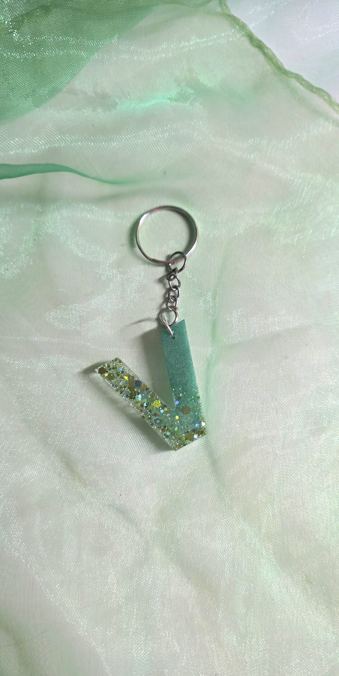 Handgefertigter Buchstaben-Schlüsselanhänger (Buchstabe V) aus Epoxidharz in sattem Grün-Weiß-Verlauf, handgegossenes Unikat mit silbernem Schlüsselring.