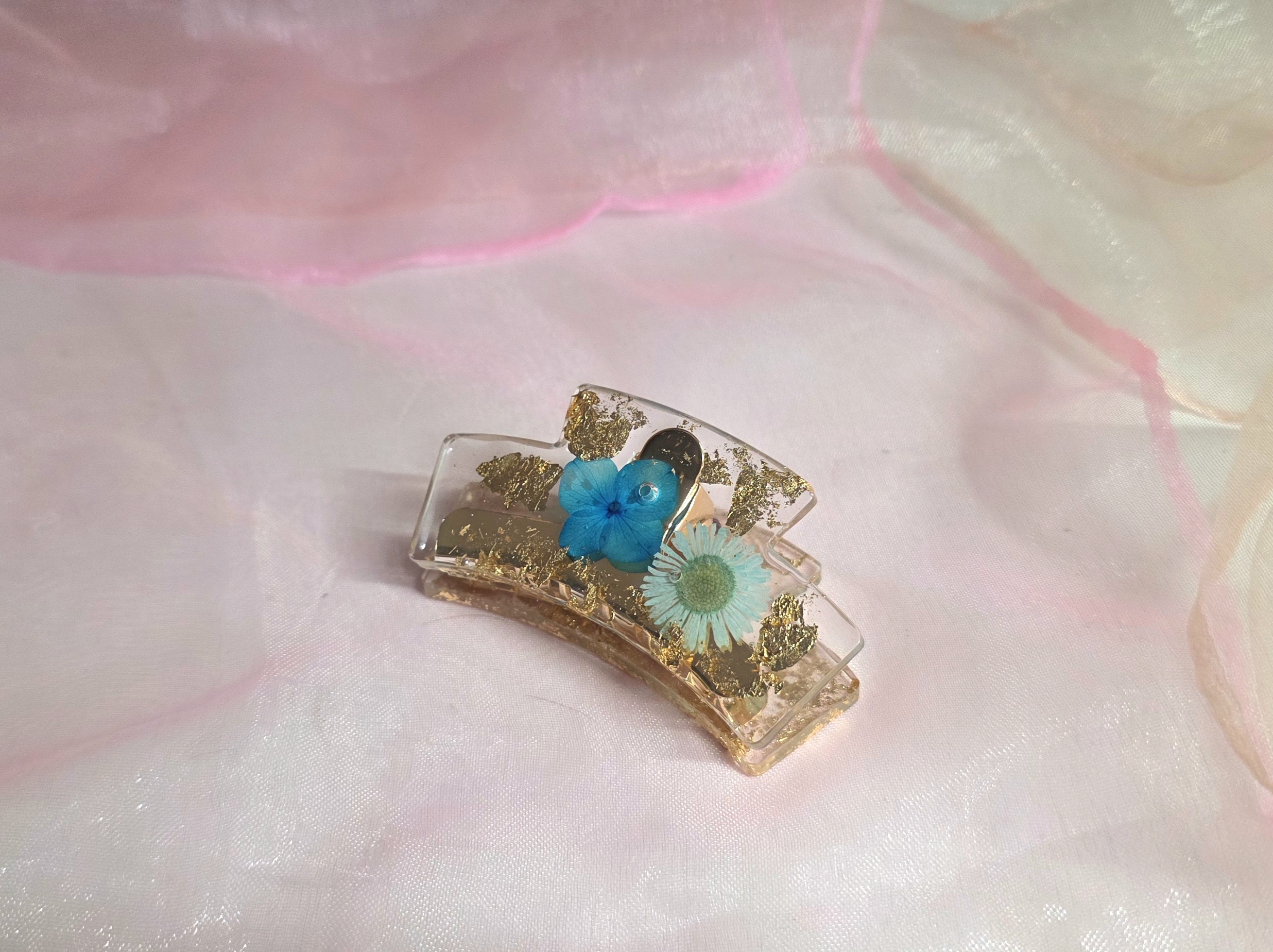 Handgefertigte Haarklammer aus Epoxidharz mit blauen Blumen und Blattgold von Traumharz.