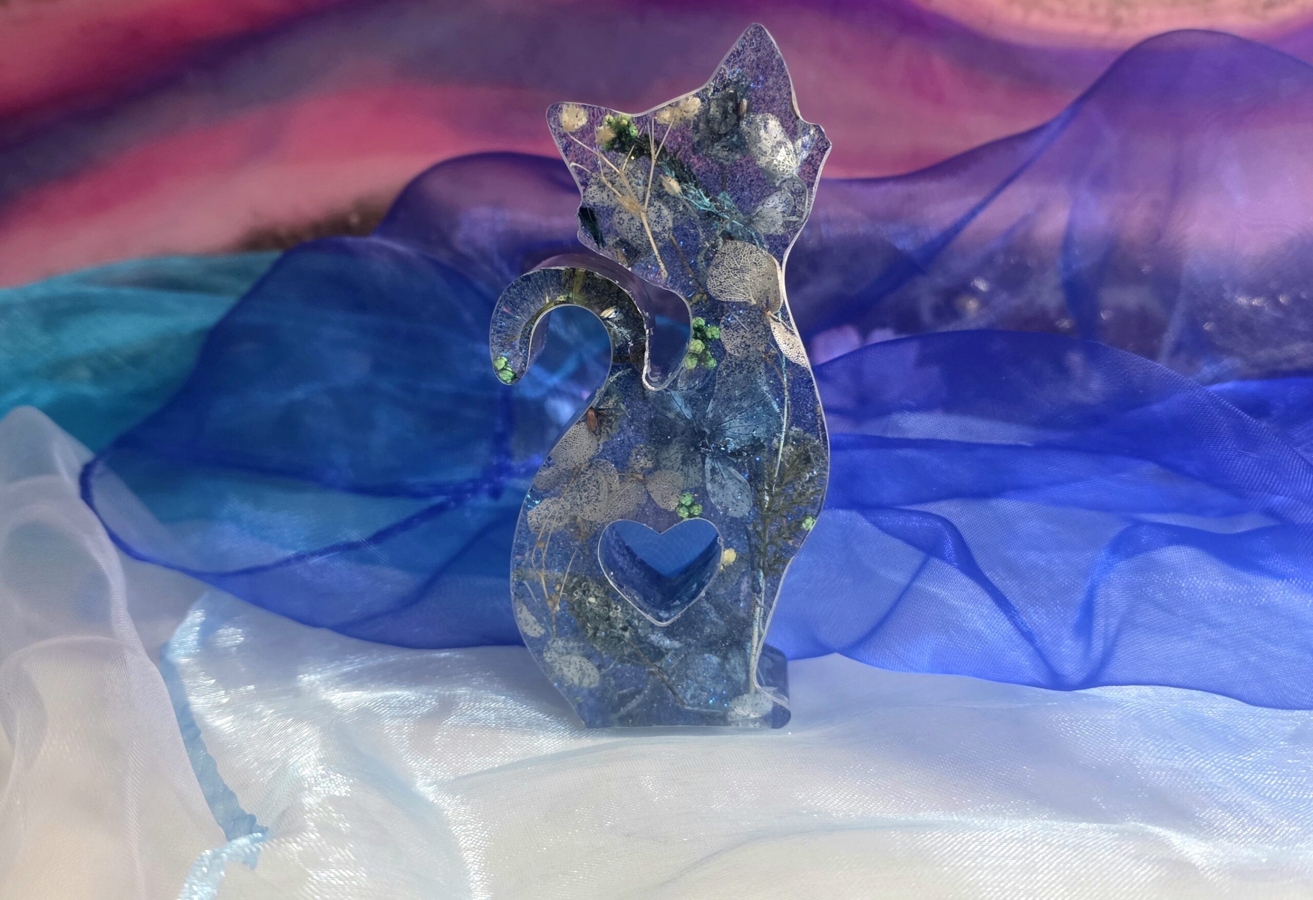 Handgefertigte Katzenfigur aus Epoxidharz mit echten blauen Trockenblumen und feinem Glitzer – Edles Resin-Unikat mit Herz-Ausschnitt von Traumharz.