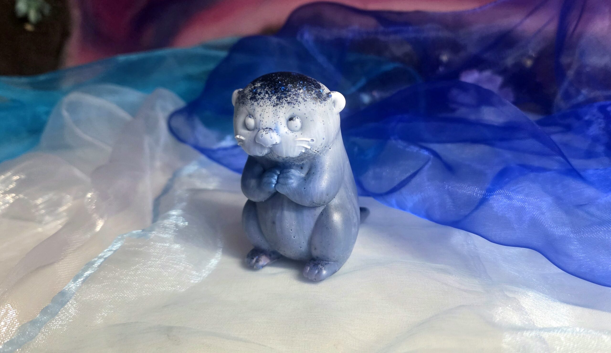 Handgefertigte Otter-Figur „Nachtpfote“ aus Epoxidharz in Nachtblau mit Sternen-Glitzer und schützenden Gumminoppen auf der Unterseite – Einzigartiges Resin-Sammlerstück von Traumharz.