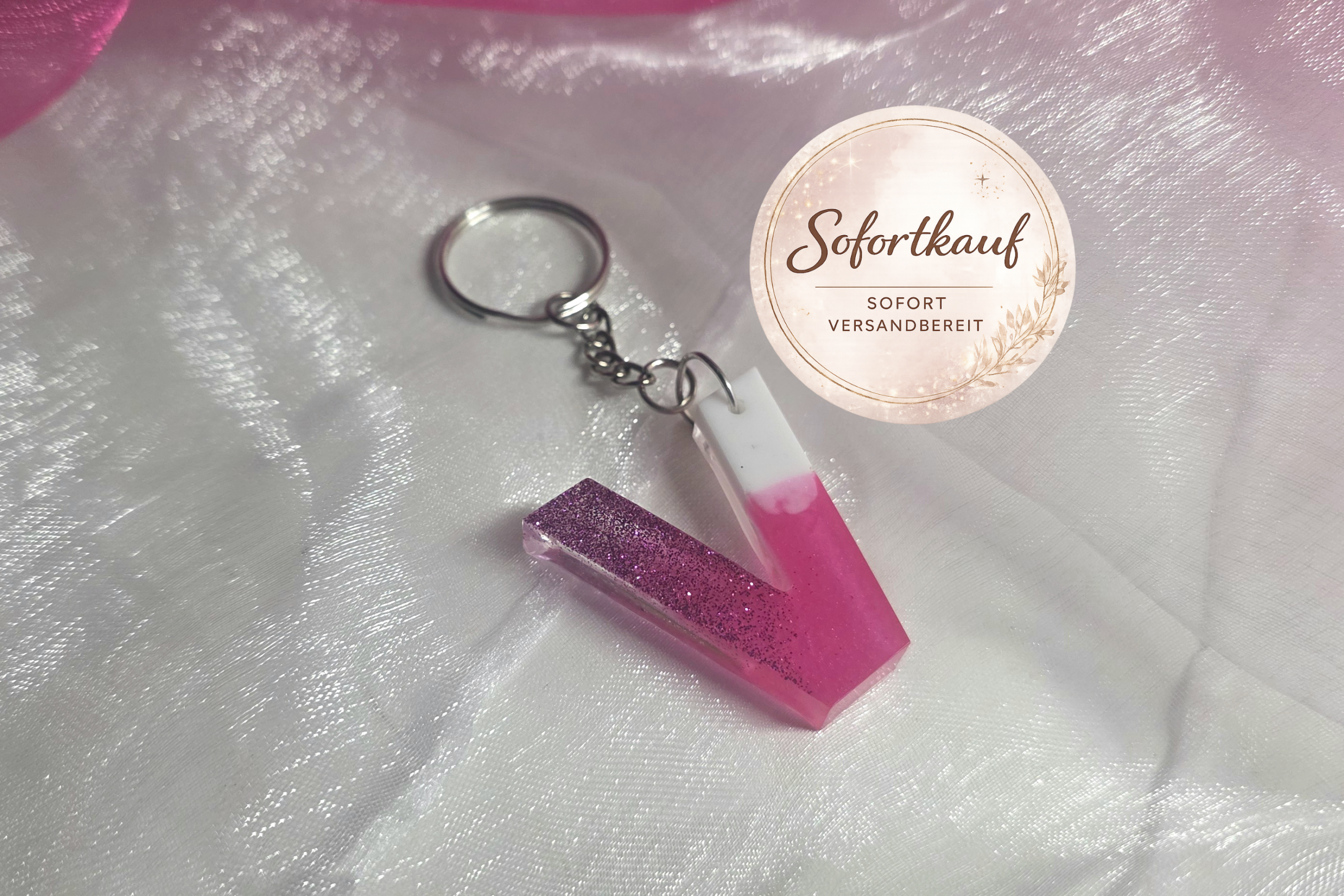 Handgefertigter Buchstaben-Schlüsselanhänger (Buchstabe V) aus Epoxidharz im edlen Farbverlauf Pink-Weiß mit glänzendem Finish und silbernem Ring.